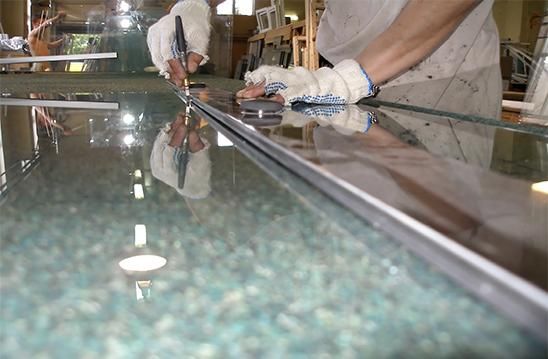 Una persona está cortando un trozo de vidrio con un par de tijeras.