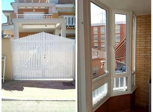 Una casa con un portón blanco y un balcón con muchas ventanas.