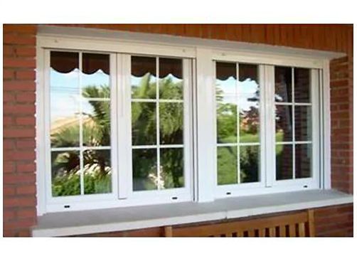 Una ventana blanca en una pared de ladrillos con un banco delante de ella.