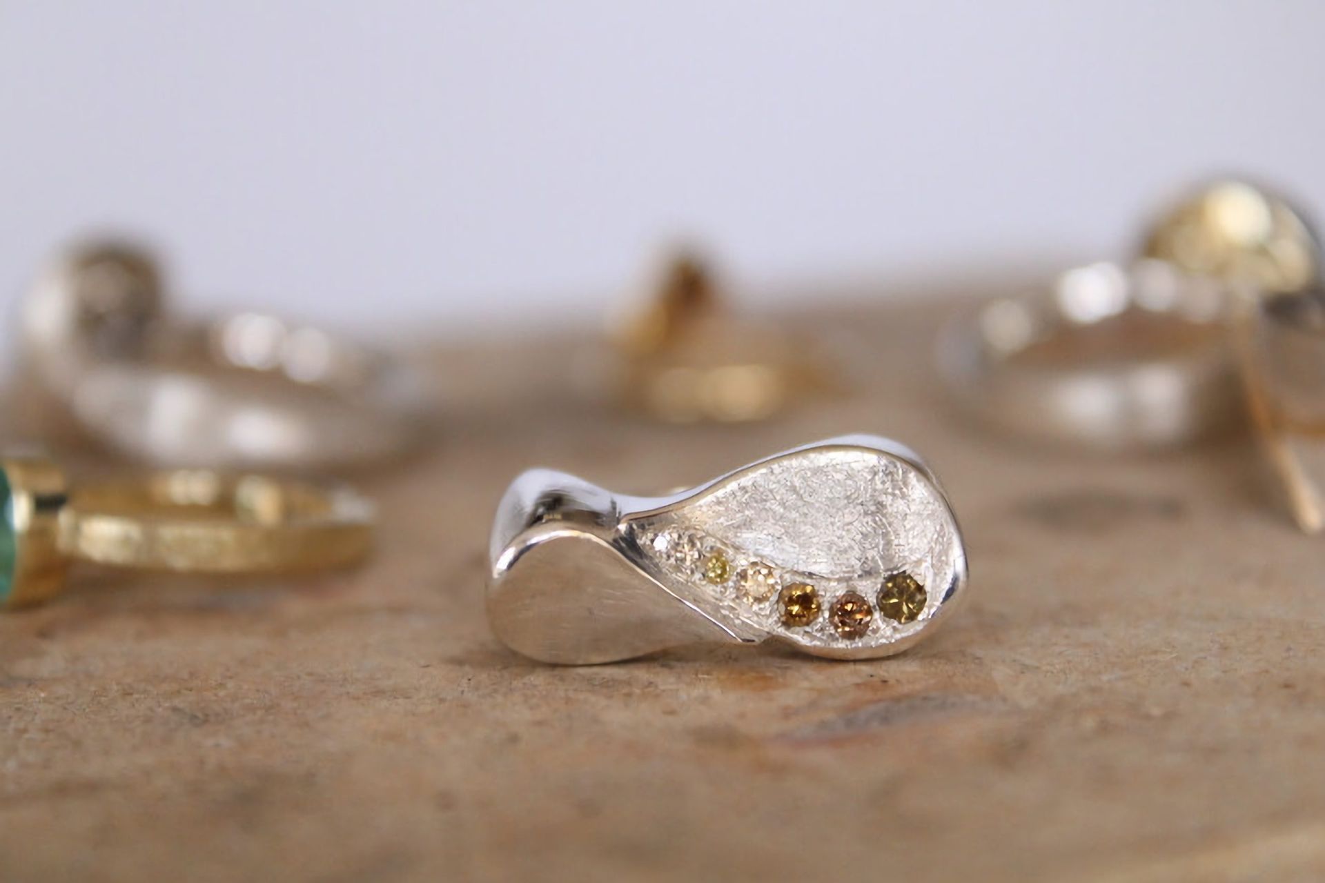 Goldschmiede Norys - weißer Ring in Tropfenform auf einem Tisch im Fokus