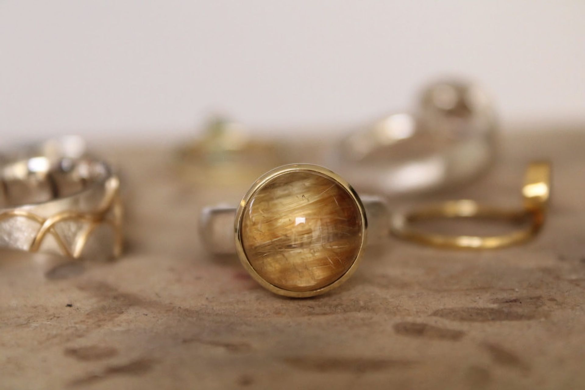 Goldschmiede Norys - brauner Ring mit rundem Schmuckstein auf einem Tisch im Fokus