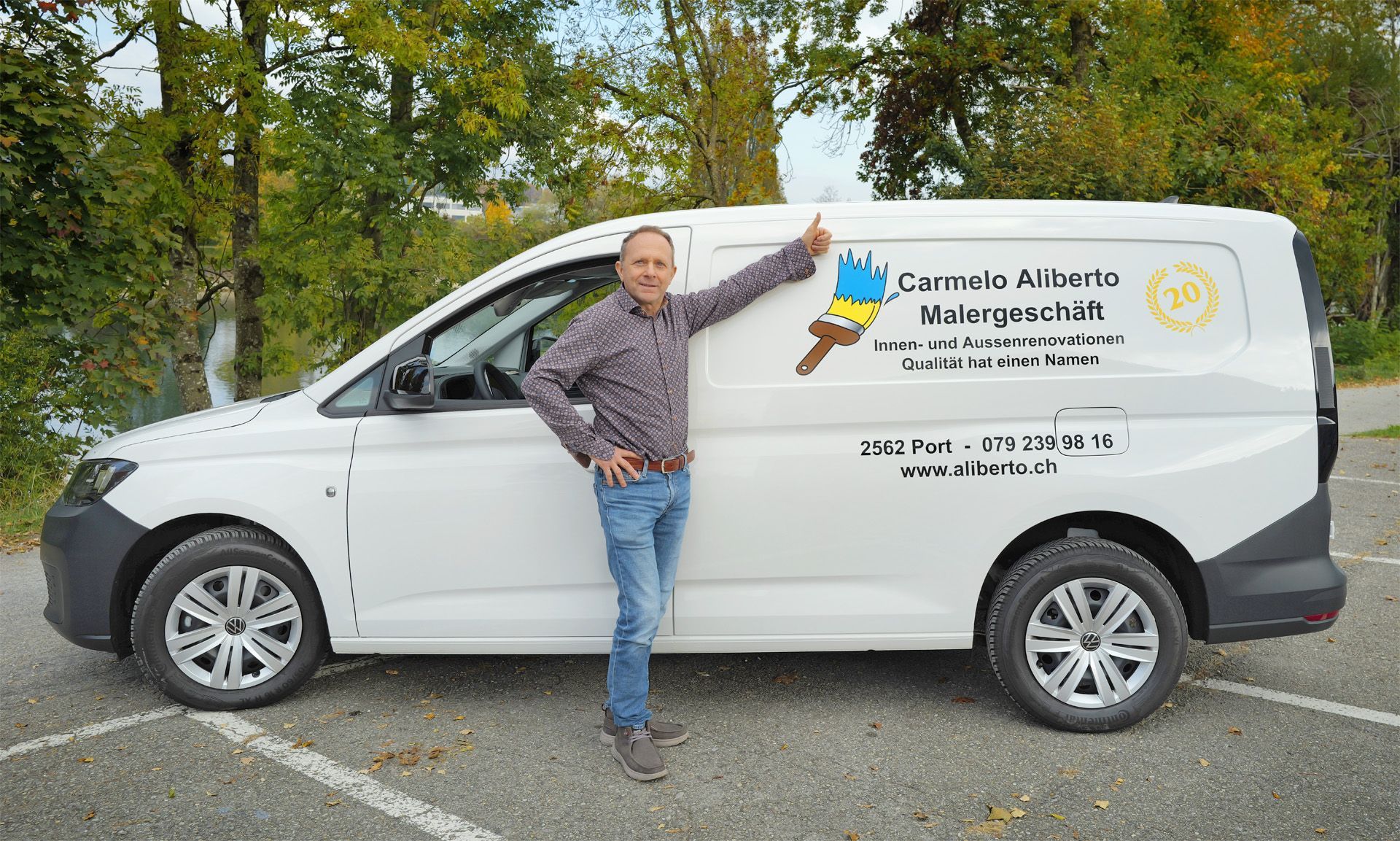 Ein Mann zeigt auf einen weissen Lieferwagen mit Firmenlogo.