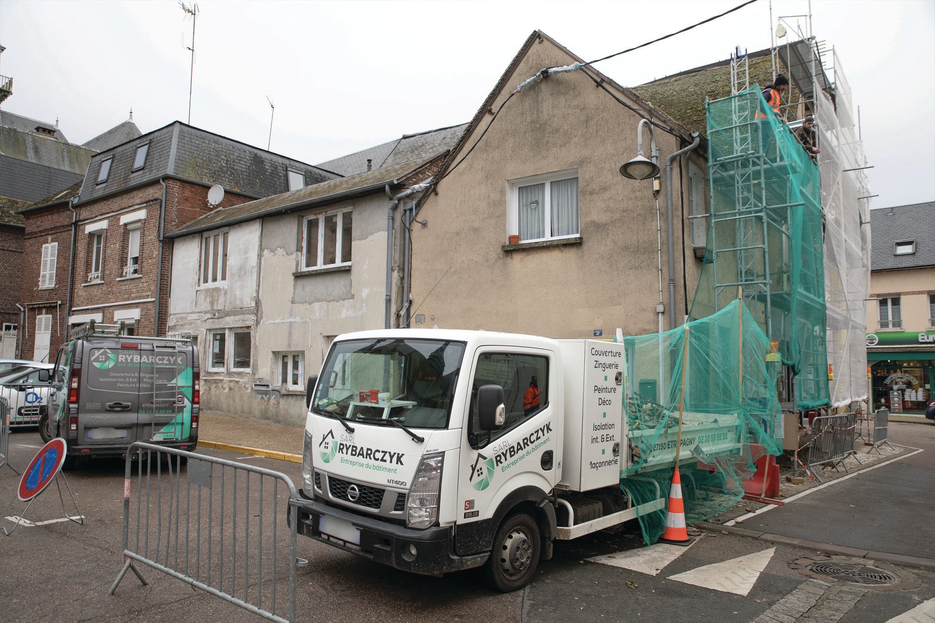 Un camion de l'entreprise garé devant un chantier de toiture