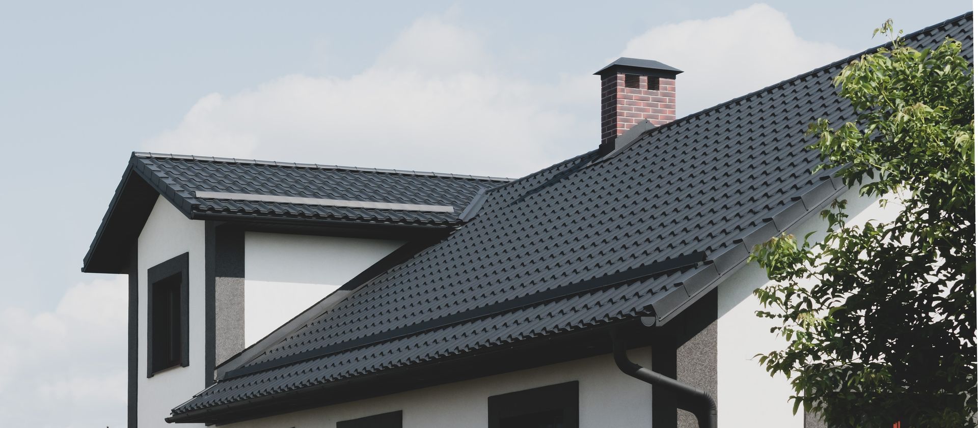 Une maison avec une belle toiture et des gouttières noires