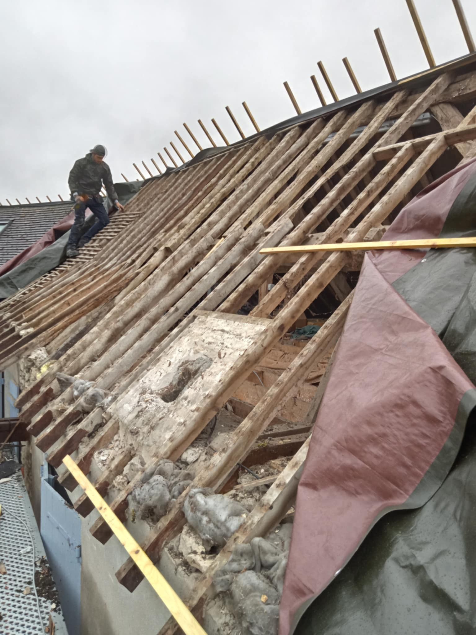 Un artisan sur une très ancienne toiture abîmé par le temps