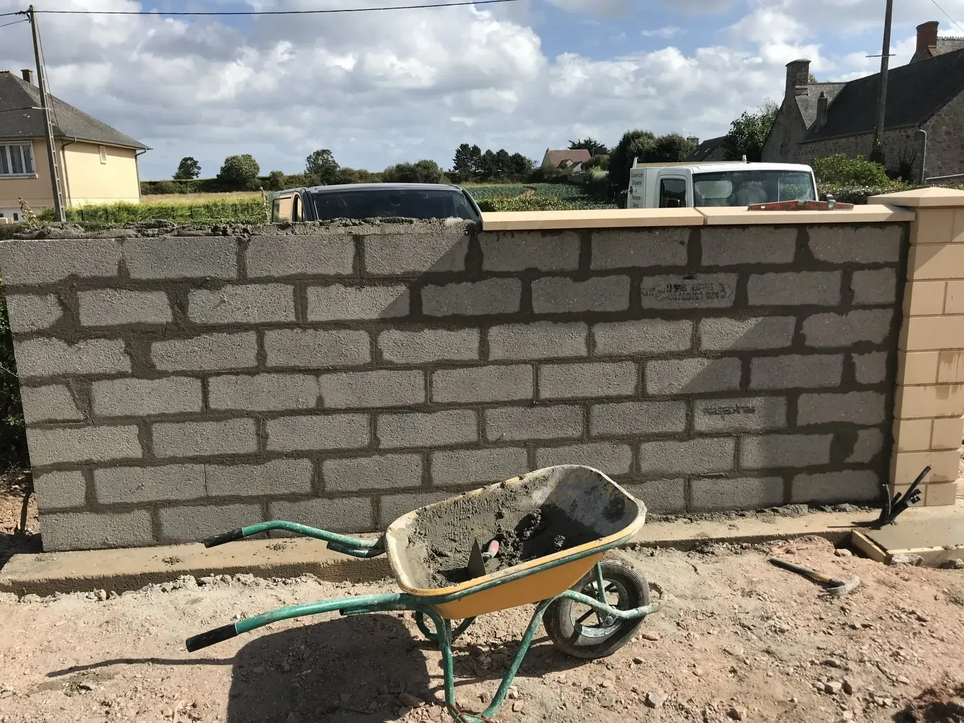 Brouette de ciment devant un mur en construction