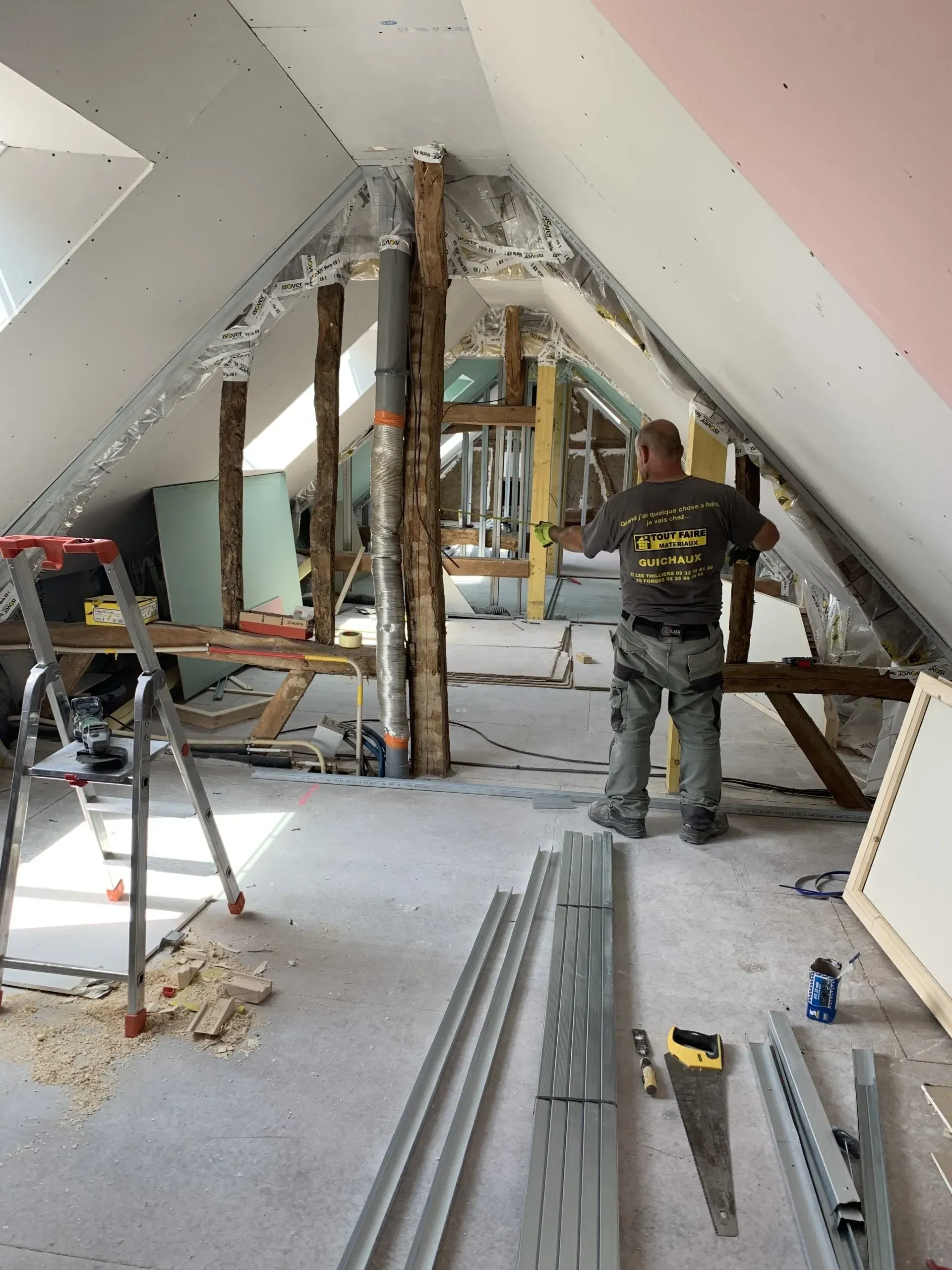 Un artisan de dos dans les combles en cours d'aménagement
