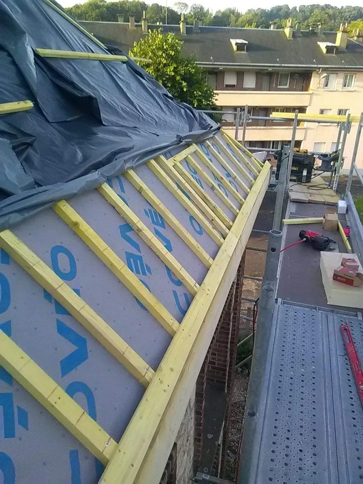 Portion de toiture en rénovation recouvert d'une bâche