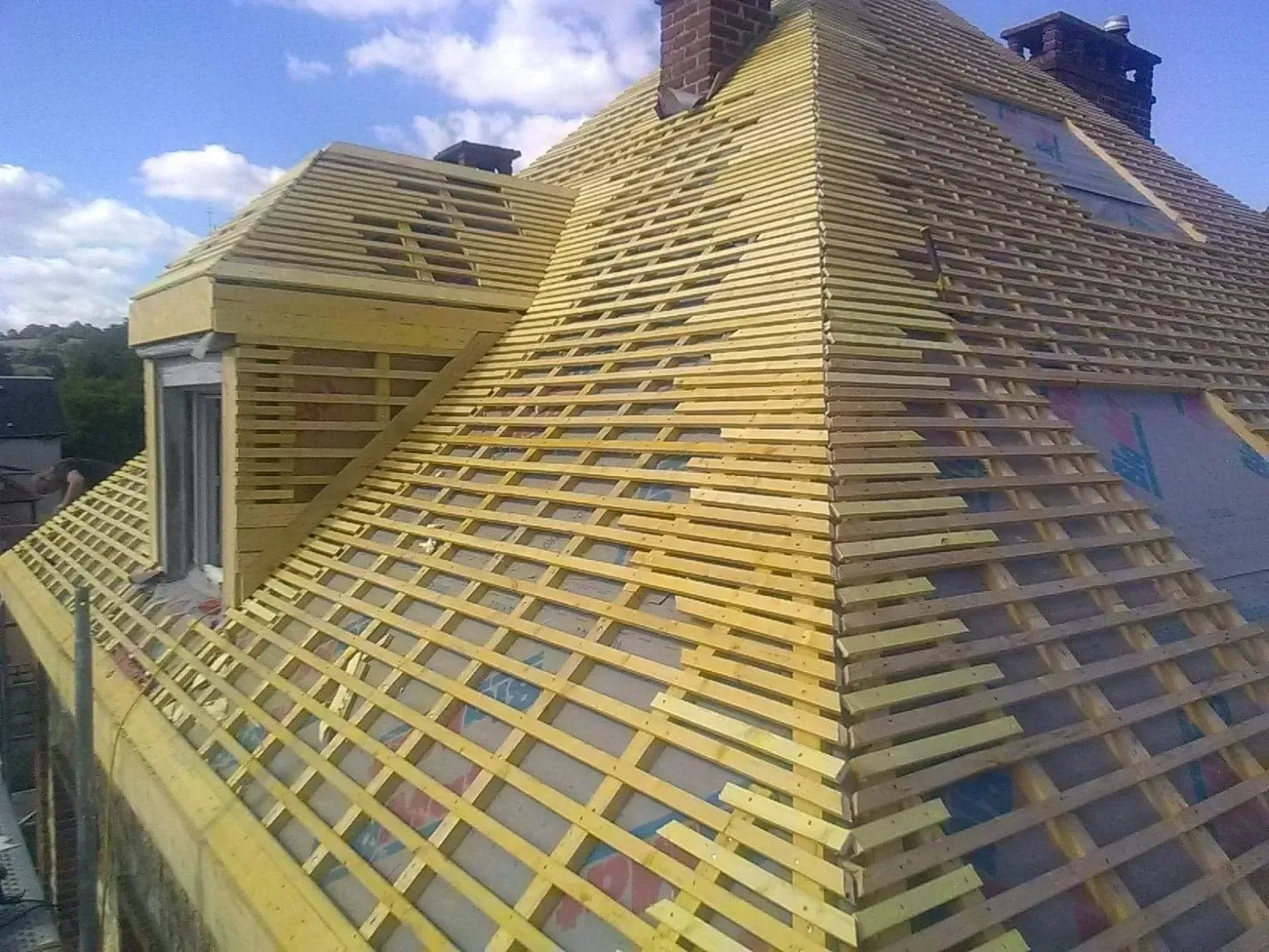 Multiples tiges de bois clair recouvrant une toiture en rénovation 03