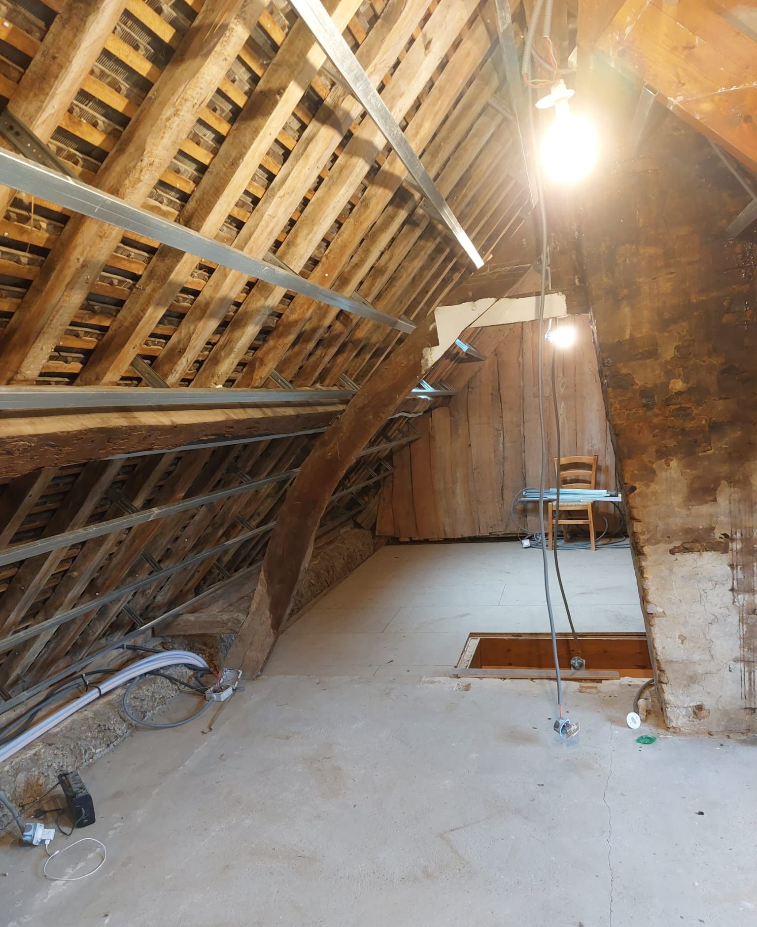 Intérieur de combles en cours de rénovation éclairé par des ampoules