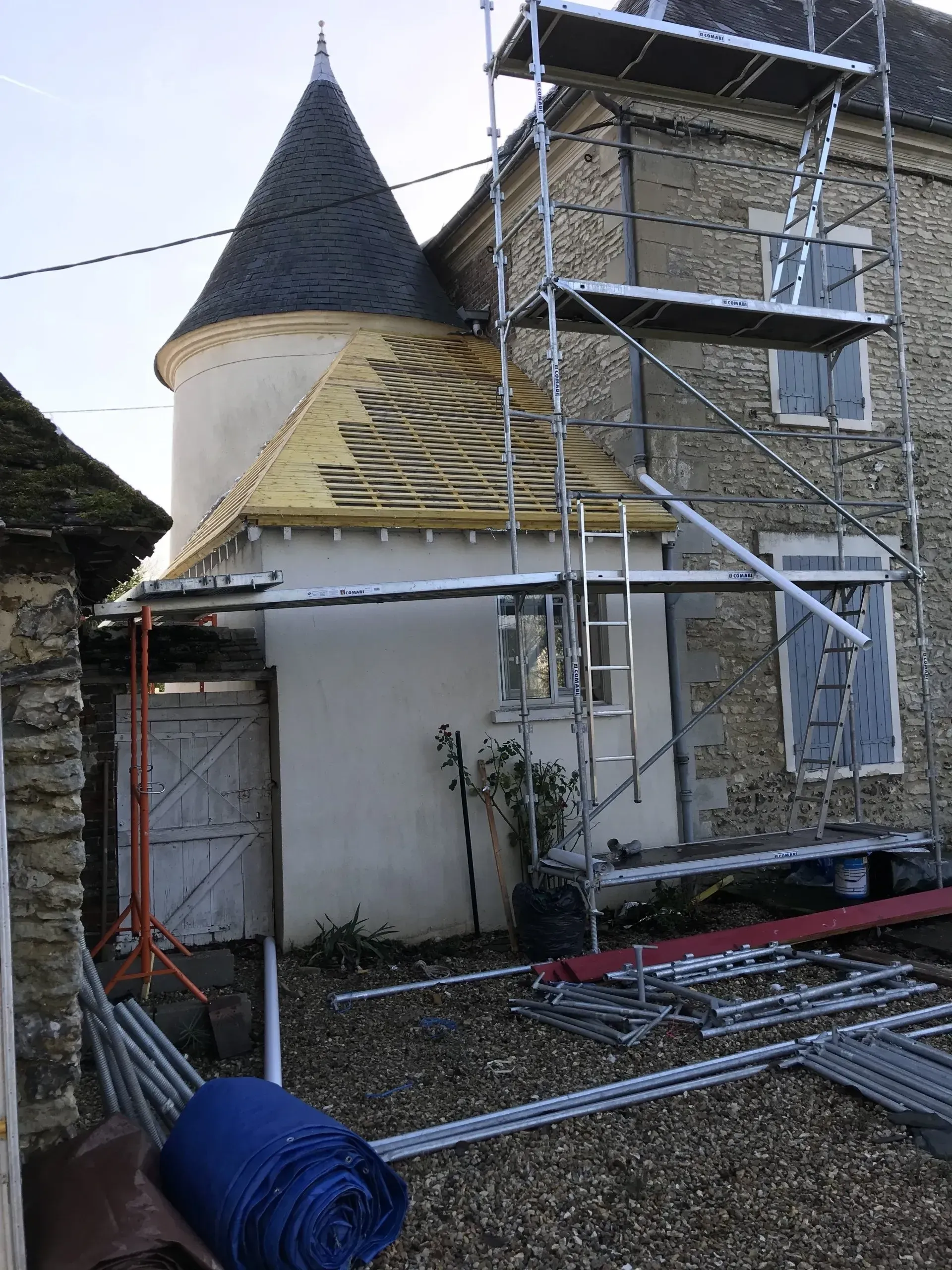 Échafaudage devant une façade de maison dont une partie de la charpente est apparente