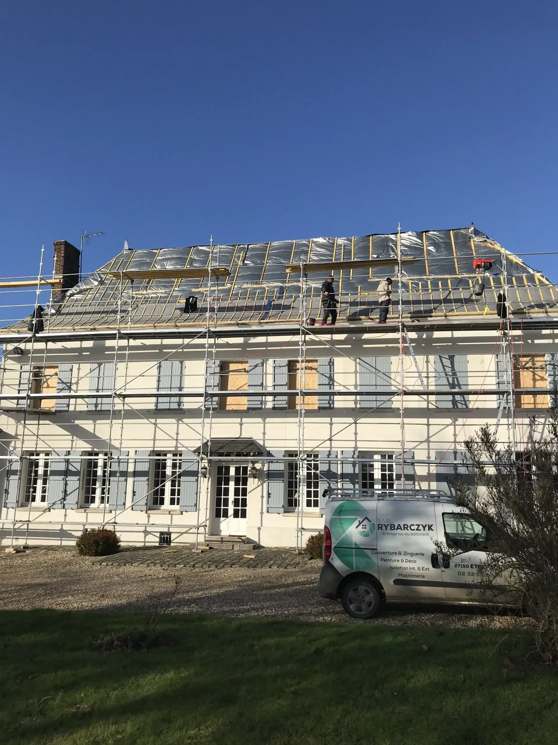 Échafaudage devant une grande habitation dont le toit est en cours de rénovation