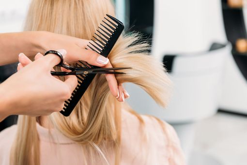 Inneneinrichtung eines Friseursalons mit Frisierplätzen, Spiegeln und einem Waschbecken. Gelbe und orangefarbene Akzentwände.