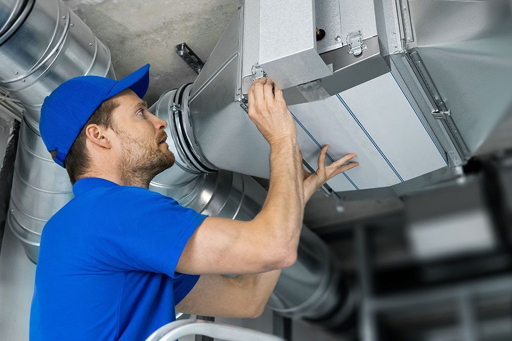 Installation de la ventilation d'un immeuble par un technicien en tenue bleu