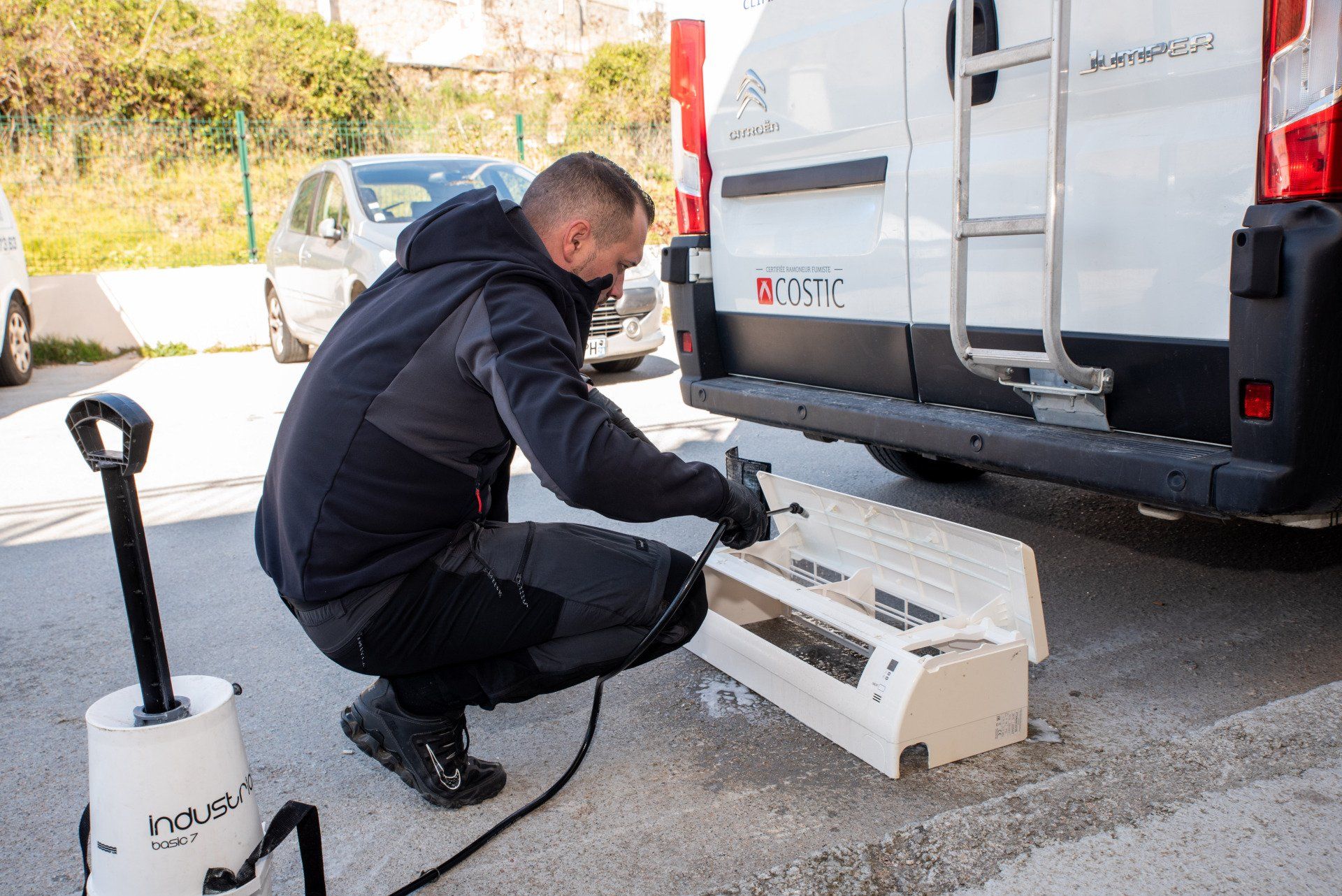 Membre de Pro Services Plus nettoyant une climatisation à l'extérieur