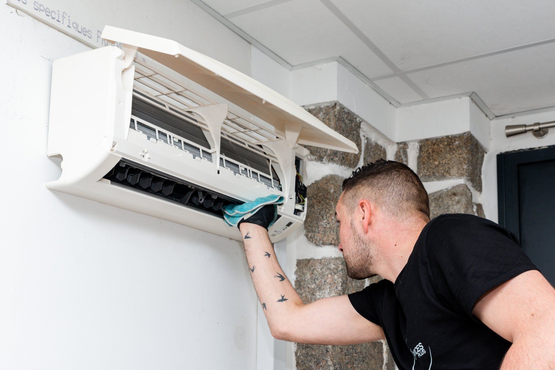 Membre de Pro Services Plus nettoyant la climatisation d'un particulier