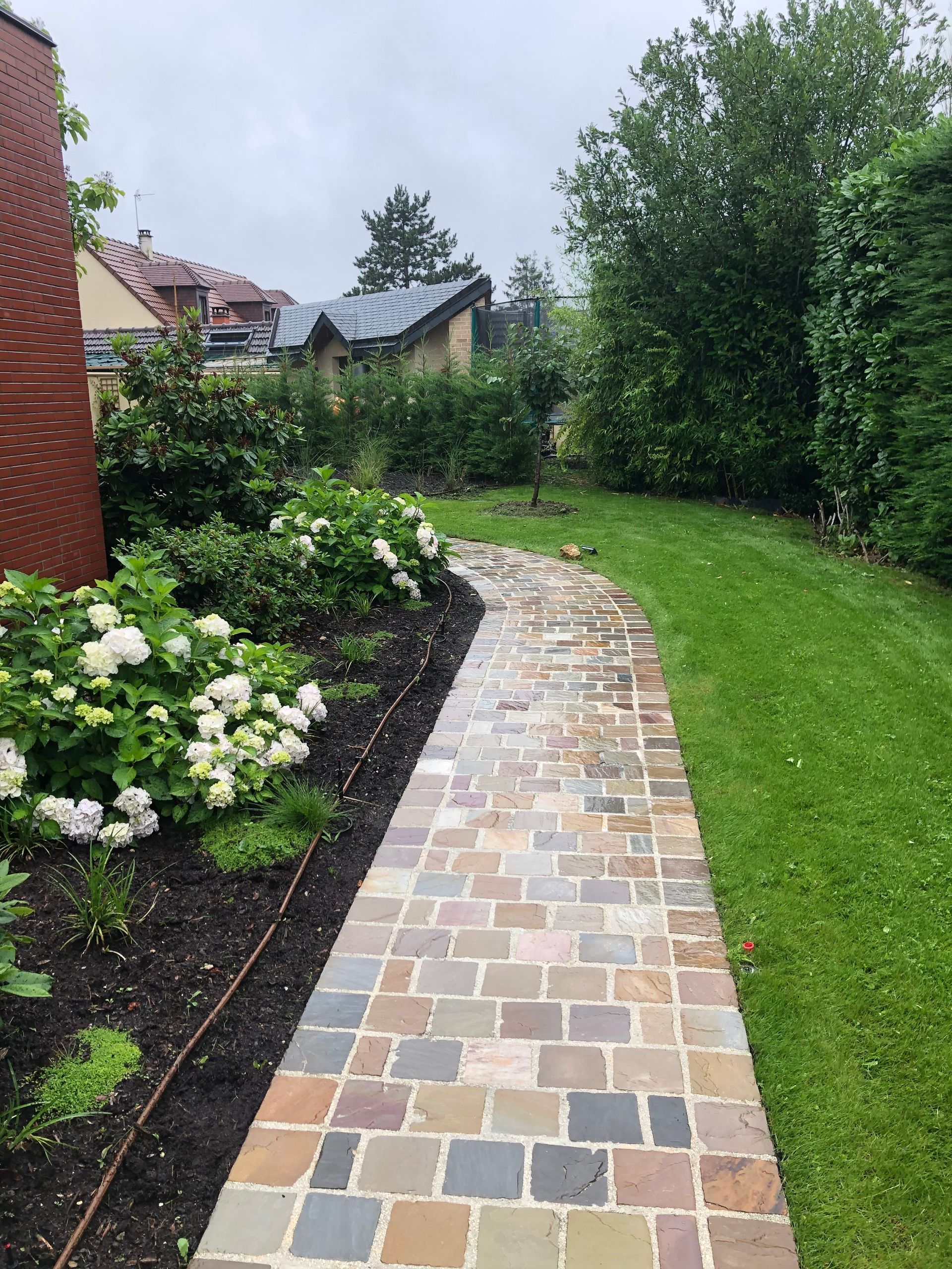 Allée en dallage et jardin avec roses blanches