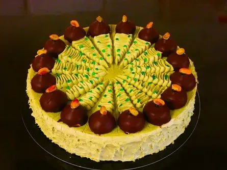 Runder Kuchen mit gelbem Zuckerguss, grünen Wirbeln und schokoladenüberzogenen Erdbeeren obenauf und am Rand.