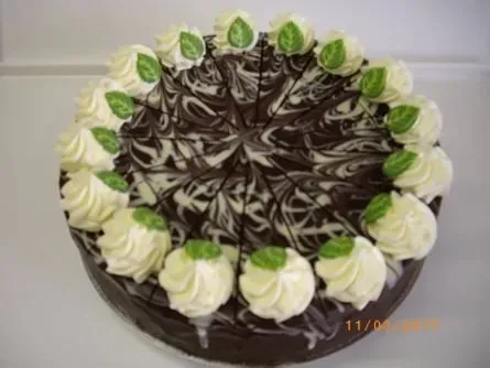 Schokoladenkuchen mit weißen und grünen Zuckergusswirbeln und Schokoladenglasur