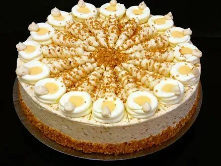Runder Sahnekuchen mit aufgespritzten Verzierungen und gehackten Nüssen auf weißem Hintergrund