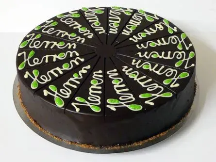 Runder Schokoladenkuchen mit schwarzem Zuckerguss und grün-weißen Spritzdekorationen obenauf