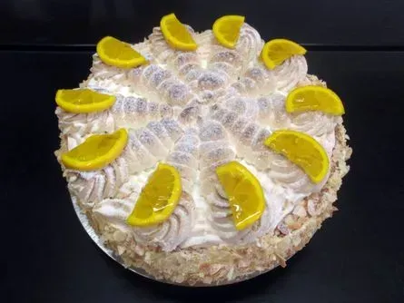Runder Kuchen mit gelbem Zuckerguss, grünen Wirbeln und schokoladenüberzogenen Erdbeeren obenauf und am Rand.