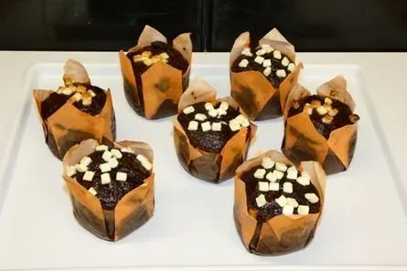 Verschiedene Schokoladen-Cupcakes mit weißer Sahne und Schokoladenglasur auf einem weißen Tablett