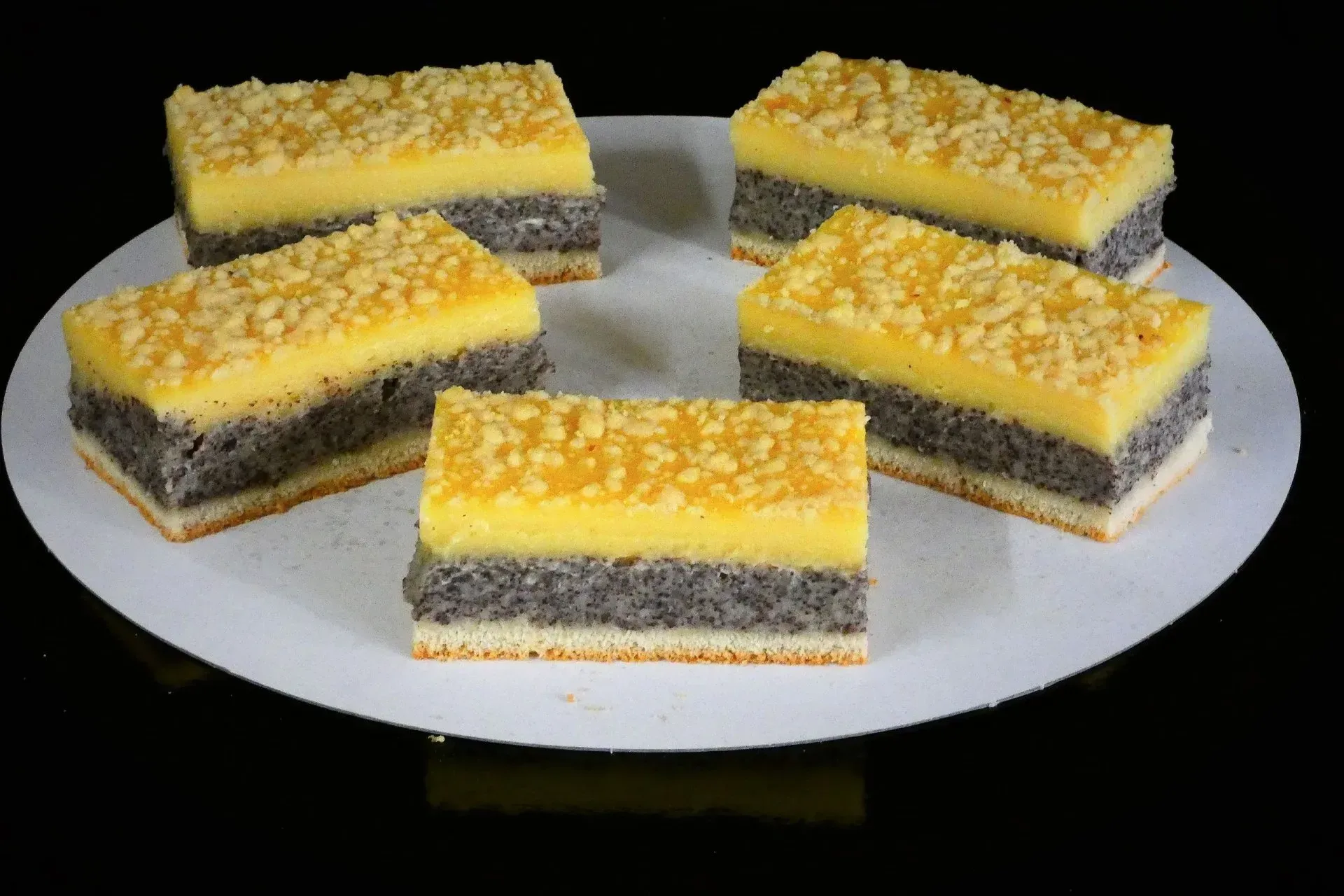 Fünf rechteckige Dessertriegel mit gelbem Belag auf einem weißen Teller