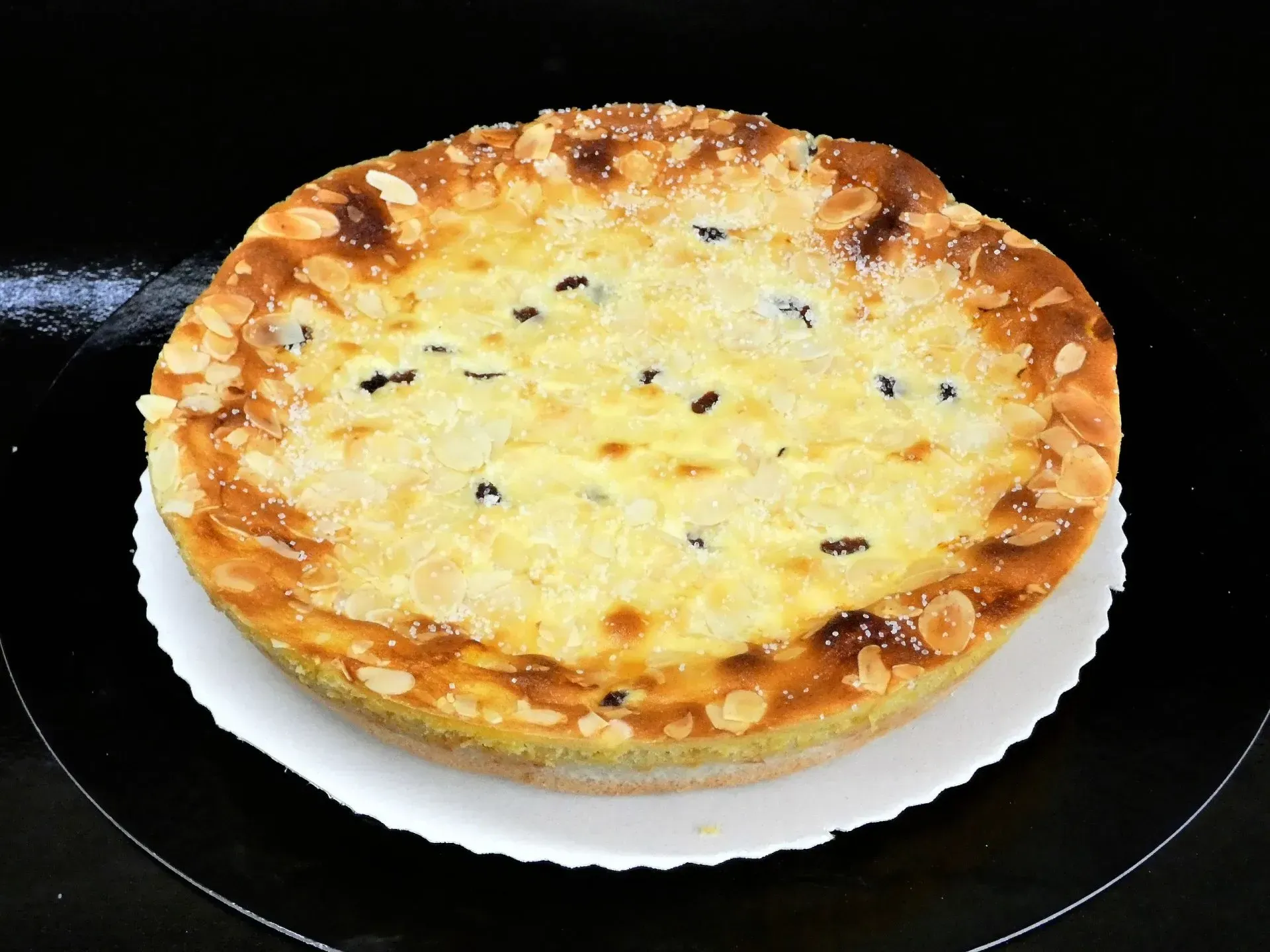 Eine mit Käse überbackene Tarte auf einem weißen Teller auf einem schwarzen Herd.
