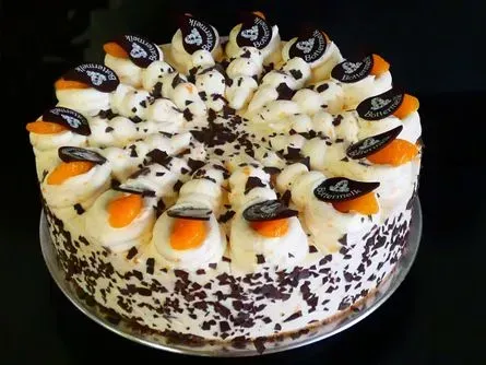 Dekorierter Kuchen mit Schokoladen- und Orangenstücken, an den Seiten mit Schokoladenraspeln verziert.