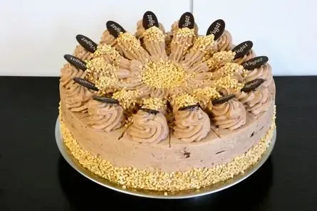 Schokoladenkuchen mit Zuckerguss, garniert mit Keksen und dekorativen Verzierungen auf einem schwarzen Tisch