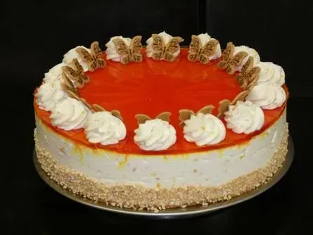 Runder Käsekuchen mit glänzend rotem Zuckerguss und Sahnehäubchen darauf, auf einem Teller