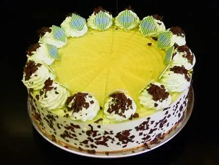 Gelber, glasierter Kuchen mit Sahnetupfen und Schokoladenraspeln an den Seiten