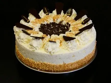 Verzierter Kuchen mit weißem Zuckerguss, Schokoladenfüllung und mit Kokosraspeln bestreuten Seiten auf einem Teller