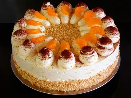 Runder Kuchen mit Orangenscheiben und Sahnetupfen auf einem Teller