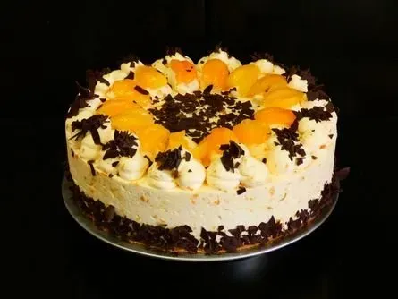 Runder Kuchen mit Orangen und Schokoladenraspeln auf einem weißen Teller