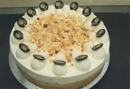 Runder Sahnekuchen mit Nüssen und schokoladenüberzogenen Stücken auf einem Teller