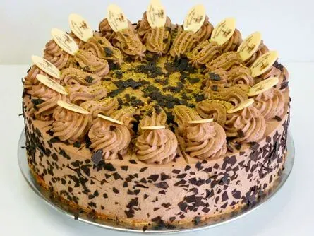 Schokoladenkuchen mit aufgespritzten Zuckergussrosetten und Schokoladenraspeln oben und an den Seiten