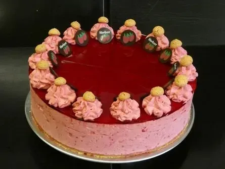 Runder Erdbeerkuchen mit glänzend roter Glasur und rosa Zuckergussrosetten auf einem goldenen Brett