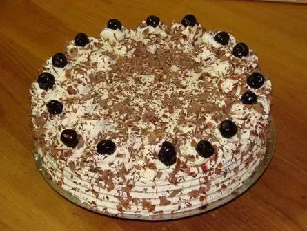 Schokoladenkuchen mit Schlagsahne, Schokoladenraspeln und Kirschen auf einem Teller