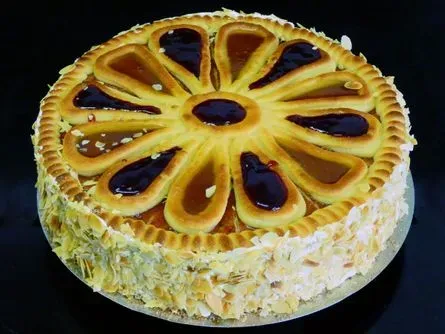 Obsttarte mit glänzendem Fruchtbelag und einem cremefarbenen Boden auf dunklem Hintergrund