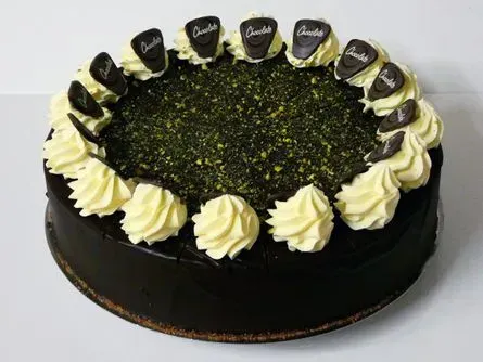 Schokoladenkuchen mit Sahnewirbeln, grünen Streuseln und kleinen Schokoladendekorationen obendrauf