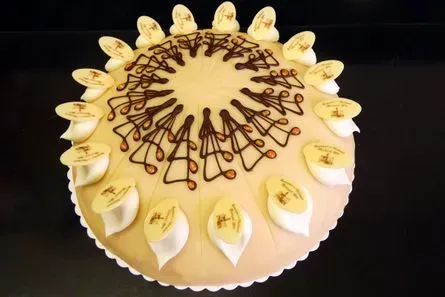 Runde Sahnetorte mit weißen Sahnehäubchen und Schokoladenglasur, von oben betrachtet
