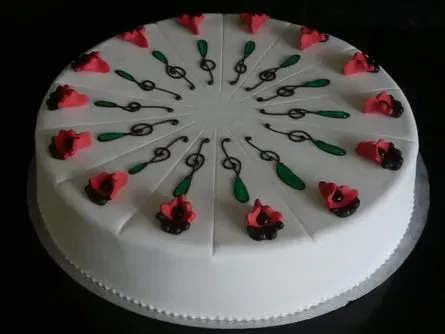 Weißer Zuckergusskuchen mit roten Rosenverzierungen und grünen Zuckergusswirbeln obenauf