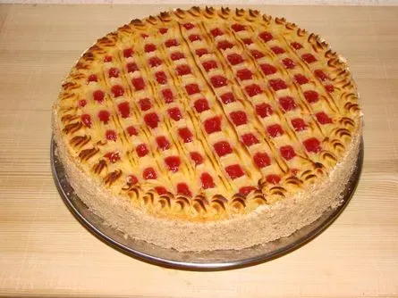 Runde Obsttarte mit Gitterboden und roten Beeren auf einem Teller