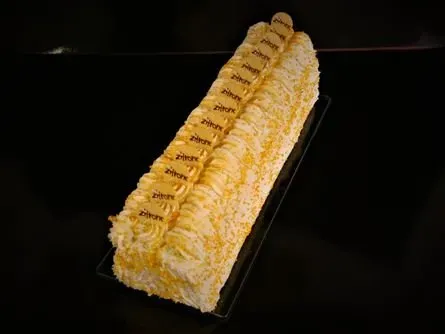 Länglicher, rechteckiger Schichtkuchen mit Sahnefüllung auf dunklem Hintergrund