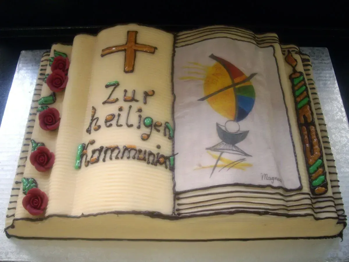 Decorated open Bible cake with cross, chalice and German text “Zur heiligen Kommunion”