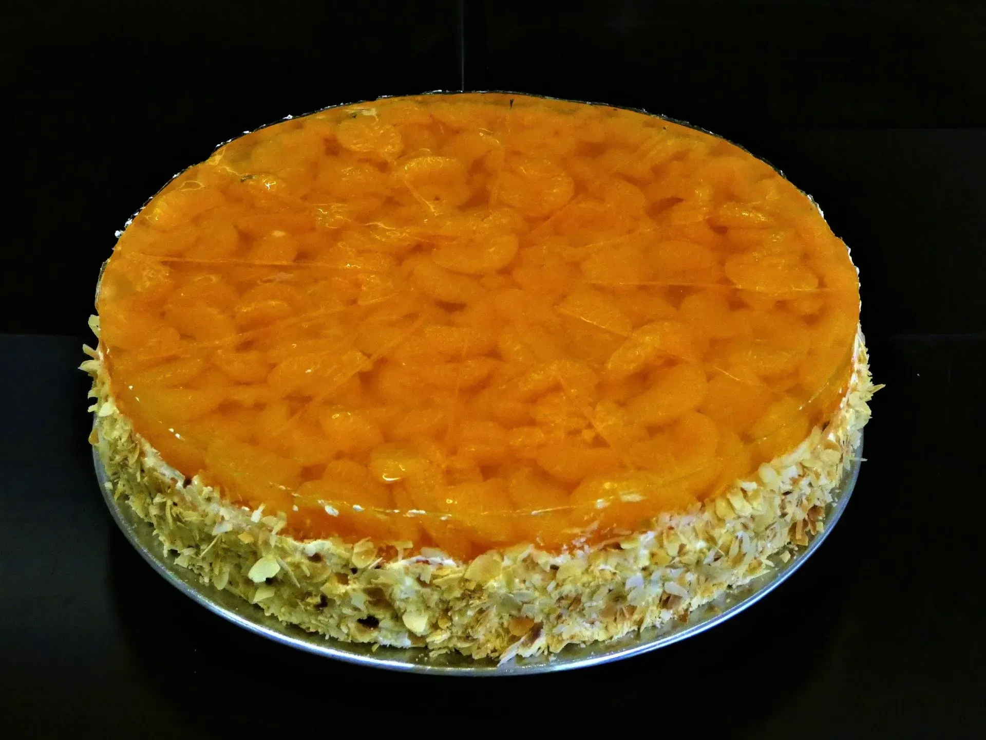Runder, mit Orangensaft glasierter Kuchen mit einer nussbestreuten Seite auf einem Teller
