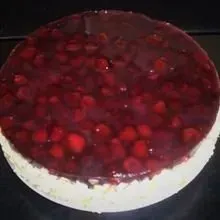 Runder, weißer Kuchen mit glänzender roter Beerenglasur und ganzen Beeren