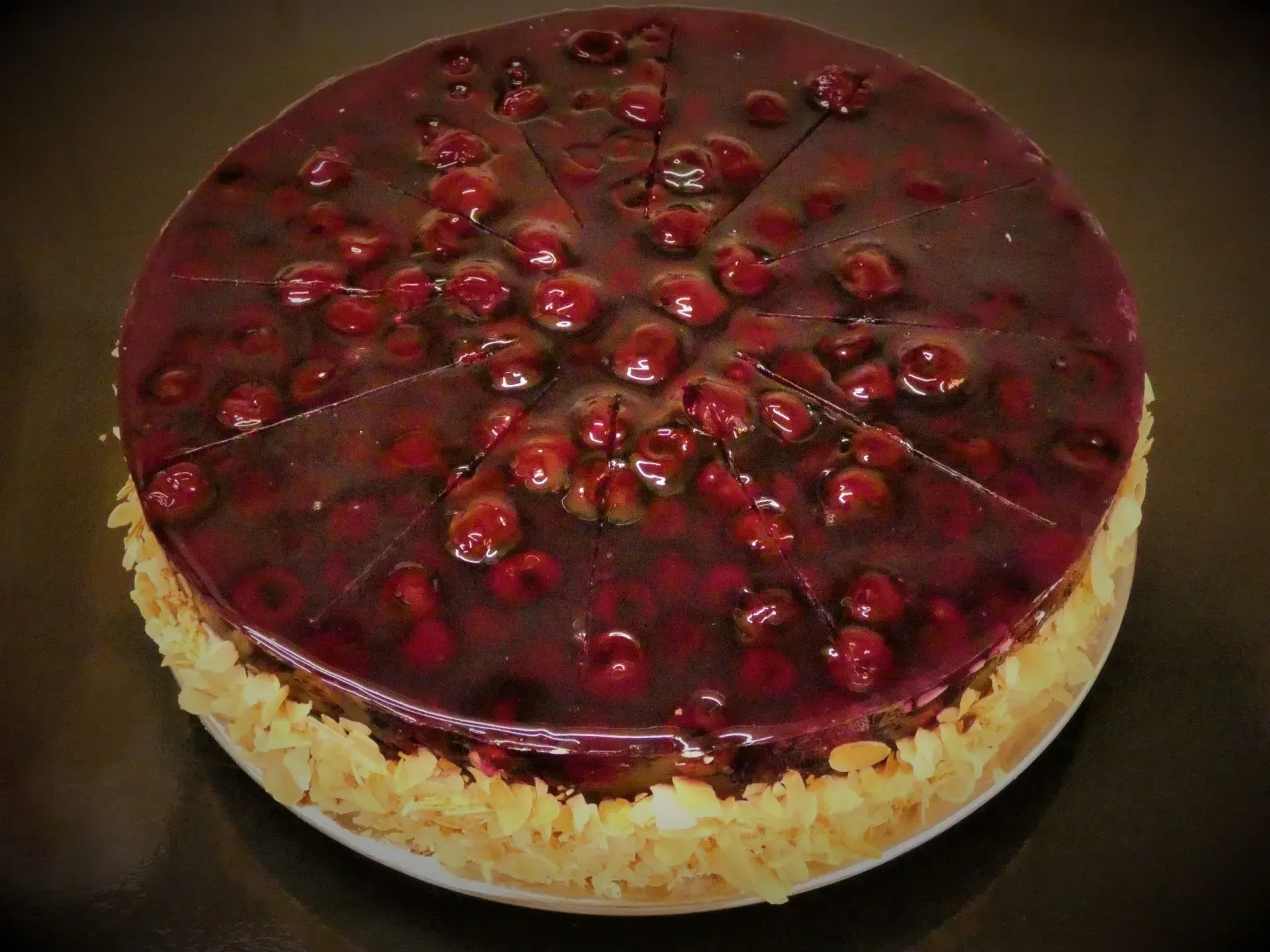 Kirsch-Käsekuchen mit glänzender roter Fruchtglasur und Mandelboden